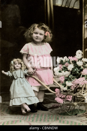 Bambina con bambola grande & Flower carrello Foto Stock