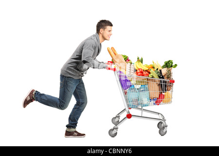 Giovane uomo che corre e spingendo un carrello pieno di cibo Foto Stock