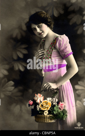 Timido Pretty Girl Holding cesto fiorito Foto Stock