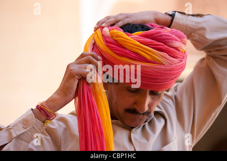 Indù guardia cerimoniale mettendo sul turbante di Rajasthani a Forte Mehrangarh di Jodhpur in Rajasthan, India settentrionale Foto Stock