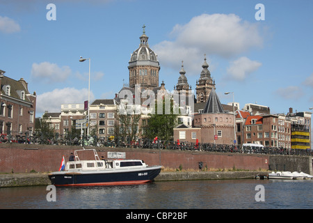 Linea di biciclette la ringhiera di argine a Prins Hendrikkade ad Amsterdam con la cupola della chiesa di San Nicola a distanza Foto Stock