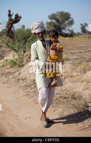 Indian Bishnoi uomo che porta il nipote vicino a Rohet nel Rajasthan, India settentrionale Foto Stock