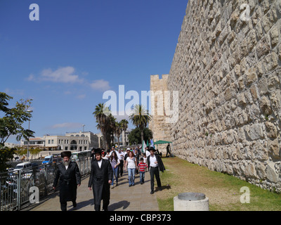 Gli Ebrei religiosi camminare con le pareti esterne della Città Vecchia di Gerusalemme nei pressi di Porta di Jaffa Foto Stock