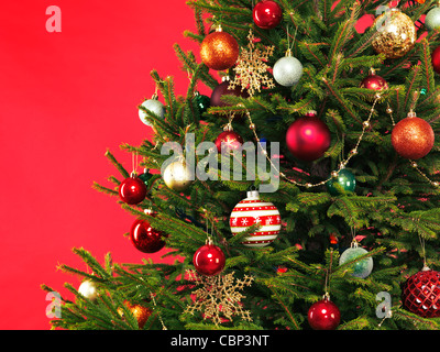 Primo piano della struttura ad albero di natale decorazione colorata sul luminoso sfondo rosso Foto Stock
