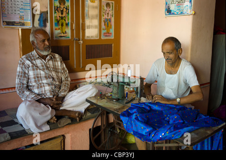 Uomo indiano con la vecchia macchina da cucire rendendo sari in Narlai village nel Rajasthan, India settentrionale Foto Stock