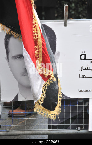 Bashar al-Assad Presidente della Siria poster e bandiera ad un anti Assad protesta al di fuori dell'Ambasciata americana a Londra Foto Stock