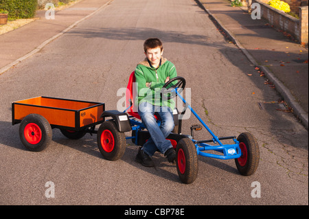 Un ragazzo di dodici anni giocando su un Berg go cart con il rimorchio in una strada del Regno Unito Foto Stock