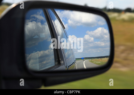 Riflettendo su strada nella veduta laterale specchio di una automobile Foto Stock