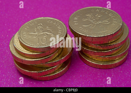 Due pile di monete di cioccolato su una rosa di sfondo glitterata Foto Stock