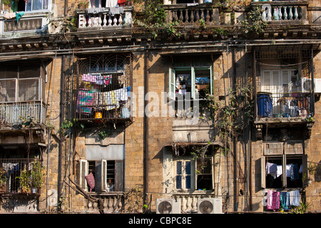 Tenement blocco chawl tradizionale sistema di alloggiamento con le unità aria condizionata e uomo nella finestra in Parel area di Mumbai, India Foto Stock