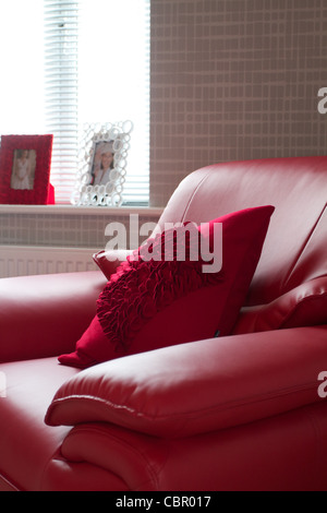 Un moderno rosso poltrona in pelle accanto a una finestra luminosa Foto Stock