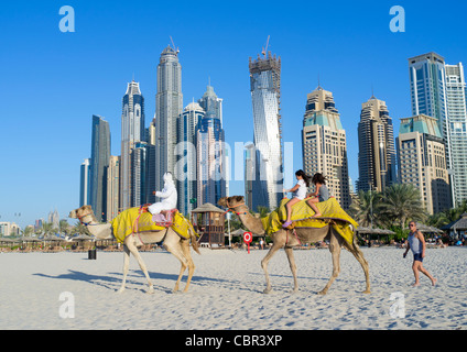 Cammelli sulla spiaggia con i turisti a Jumeirah con nuovi edifici ad alta nella nuova Dubai negli Emirati Arabi Uniti Foto Stock