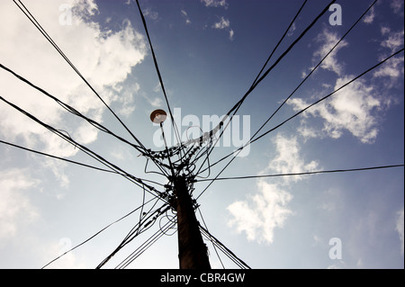 Silhouette di una lampada posta fotografati contro un cielo blu e nuvole bianche. Più fili sono collegati a questo post. Sri Lanka Foto Stock