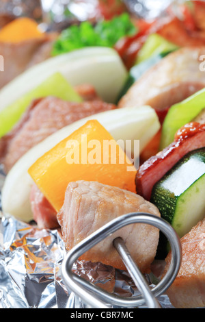 La carne di maiale e spiedini di vegetali in lamina di alluminio Foto Stock