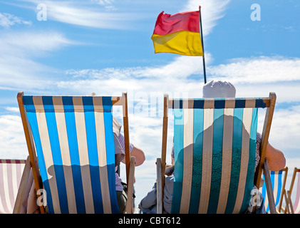 Due donne in pensione e anziane sono sedute in sedie a sdraio e si rilassano sulla spiaggia dell'oceano. Foto Stock