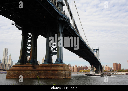 Cielo grigio visualizza rimorchiatore a traino muovendo East River verso mid-span Manhattan Bridge, dal traghetto Empire-Fulton Park, Brooklyn, New York Foto Stock