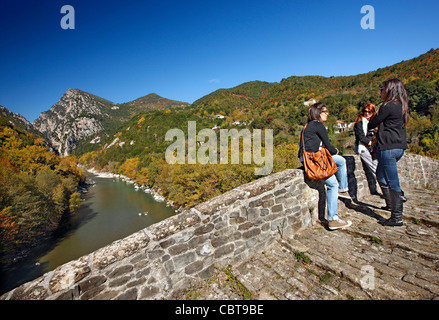 Giovani donne parlando all'antica pietra ponte arcuato di Plaka, montagne Tzoumerka, Ioannina, Epiro, Grecia. Foto Stock