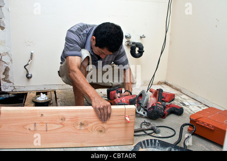 Uomo ispanico dal Messico il suo lavoro di costruzione business negli USA sostituisce la trave di supporto al piano di sopra bagno signor © Myrleen Pearson Foto Stock