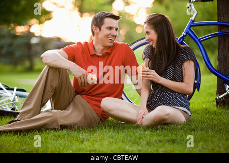 Caucasian giovane seduto in erba mangiando il pranzo Foto Stock