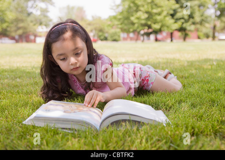 Ragazza ispanica posa in erba libro di lettura Foto Stock