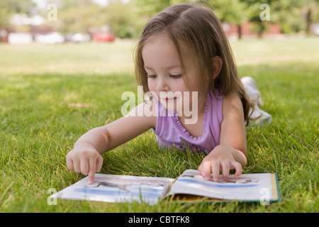 Ragazza ispanica posa in erba libro di lettura Foto Stock