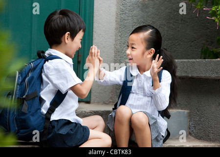 Scuola di due bambini che giocano al di fuori Foto Stock