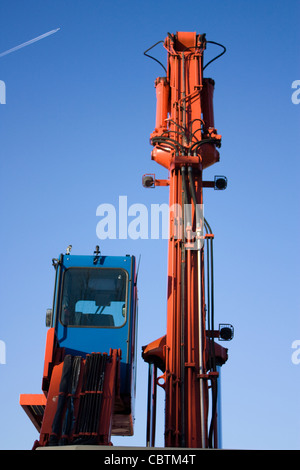 Escavatore rosso blu lavoro potenza di sabbia Foto Stock