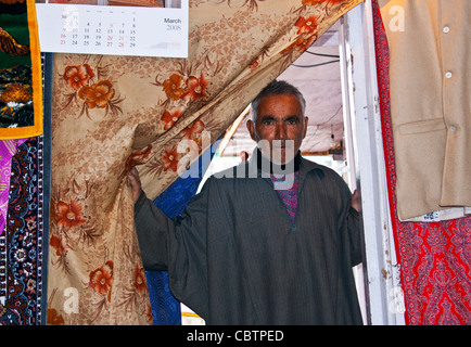 Un negoziante del Kashmir in un tessuto e negozio di articoli da regalo in dal lago il mercato galleggiante. Foto Stock