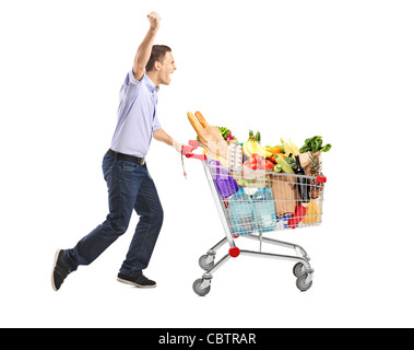 Uomo euforico spingendo un carrello pieno di cibo Foto Stock