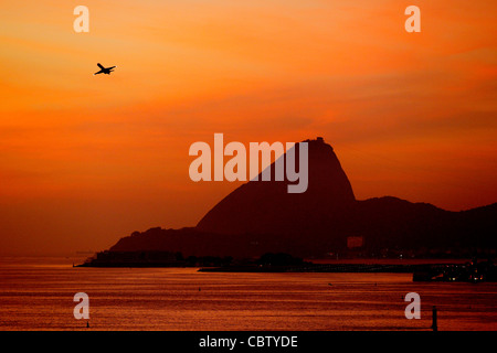 Sugarloaf è una delle principali attrazioni turistiche di Rio de Janeiro. Un aereo a decollo dal vicino aeroporto Santos Dumont. Foto Stock