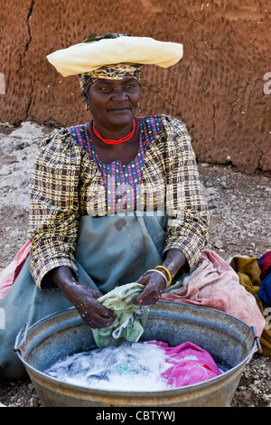 Herero donna lavando vestiti, Damaraland, Namibia Foto Stock