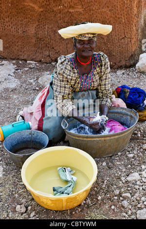 Herero donna lavando vestiti, Damaraland, Namibia Foto Stock