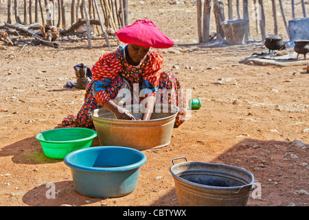 Herero donna lavando vestiti, Damaraland, Namibia Foto Stock