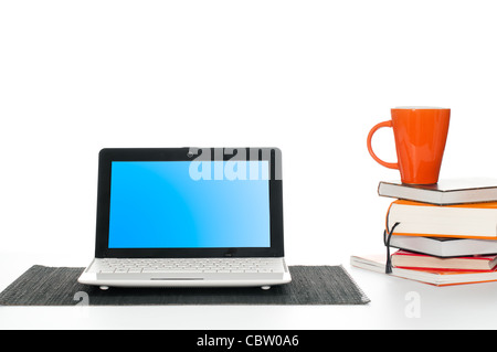 Il lavoro di ufficio scrivania con computer laptop, pila di libri e la tazza di caffè Foto Stock