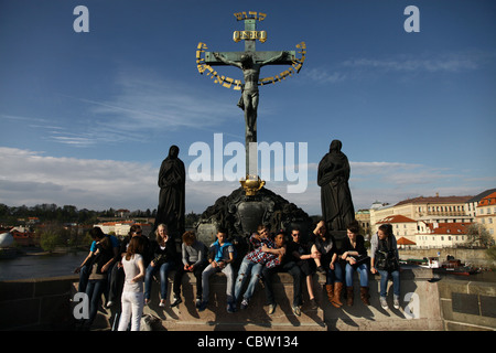 Gli scolari ceca ubicazione al di sotto di statue raffiguranti Gesù sulla croce circondata dalle parole ebraiche dalla preghiera ebraica nota come Kedushah in Ponte Carlo a Praga Repubblica Ceca Foto Stock