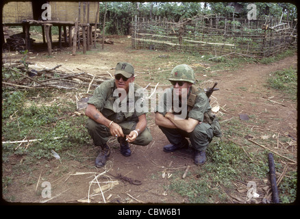 I soldati USA squatting in villaggio nella quarta divisione di fanteria e l'area di operazioni di guerra del Vietnam pleiku Foto Stock