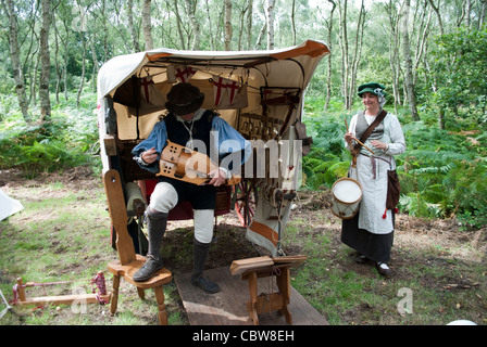 L uomo e la donna vestita come musicisti medievale di fronte ad una tenda con alberi in riproduzione in background organetto di barberia e tamburo Foto Stock