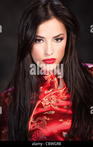 Pretty Woman in Red Cheongsam su sfondo scuro Foto Stock