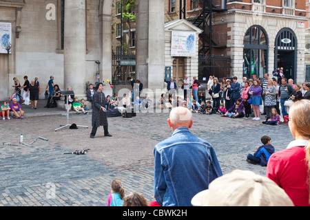 I turisti e gli amanti dello shopping e un attore di strada al Covent Garden di Londra, Inghilterra. Foto Stock
