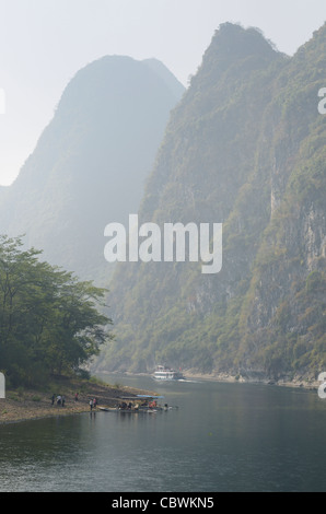 La nave di crociera e visite turistiche zattere sul vago fiume Li in Cina tra le alte vette carsiche del Guangxi Foto Stock