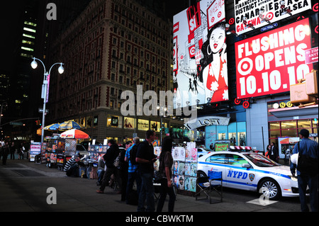 Night Shot neon cartelloni, edifici, persone NYPD auto parcheggiate sul marciapiede di stallo d'arte, West 42nd Street a Broadway, New York Foto Stock