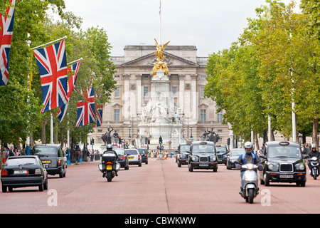Automobili e biciclette la guida e i pedoni a camminare sul Mall di fronte a Buckingham Palace. Foto Stock