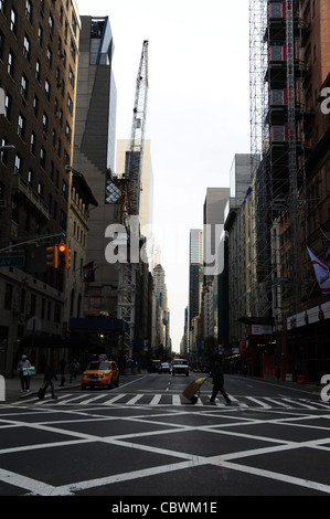 Cielo grigio " urbano " vicolo ritratto uomo spingendo carrello a mano attraversamento pedonale, West 57th Street 7th Avenue intersezione, New York Foto Stock