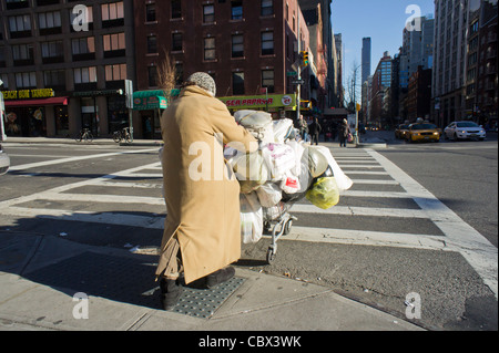 Donna con i suoi possedimenti su un carrello attraversa la Settima Avenue nel quartiere di Chelsea di New York Foto Stock