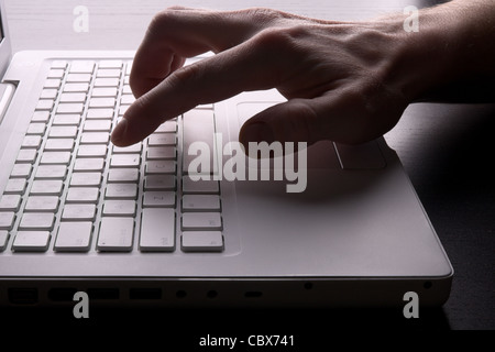 Man digitando su laptop bianco in retroilluminato. Close-up scena. Foto Stock