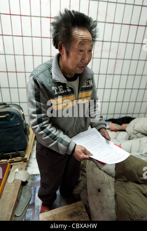 Pechino. Il sig. Wang ShiQuan, una persona senza dimora che vivono in un sotterraneo tunnel pedonale mostra una tesi che egli sta lavorando a. Foto Stock