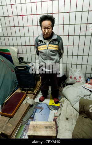 Pechino. Il sig. Wang ShiQuan, una persona senza dimora che vivono in un sotterraneo tunnel pedonale, in piedi tra i suoi beni. Foto Stock