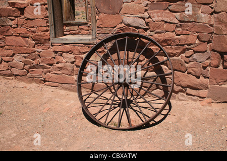 Antiquariato ruota di ferro si appoggia contro un muro di pietra a Lees Ferry , Arizona Foto Stock