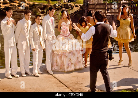 Un formalmente vestito ragazza in un Cerritos, CA, parco pone per un fotografo con la sua "corte d' onore alla sua Quinceanera Foto Stock