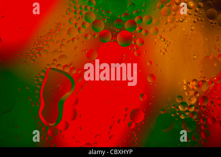 Olio e acqua con il rosso, il verde e il giallo dello sfondo. Foto Stock